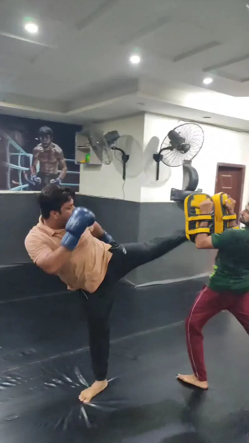 A student kicking a pad held by a coach
